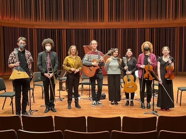 Acht Musikerinnen und Musiker mit Instrumenten auf einer Konzertbühne