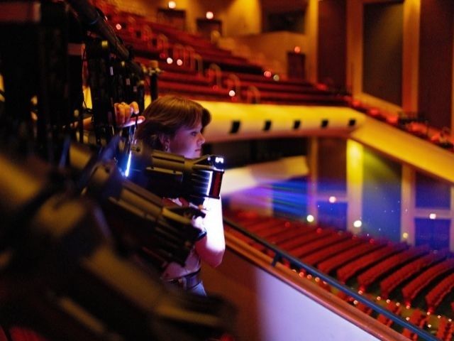 Junge Musikerin mit Instrument hinter den Kulissen eines Konzertsaals
